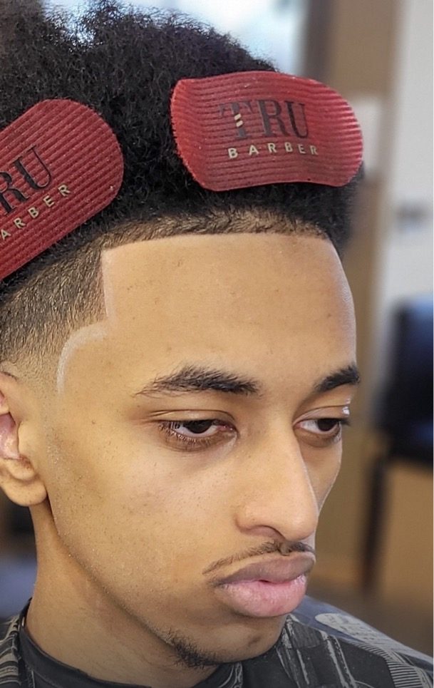 Curly top with a low fade and a sharp razor line-up